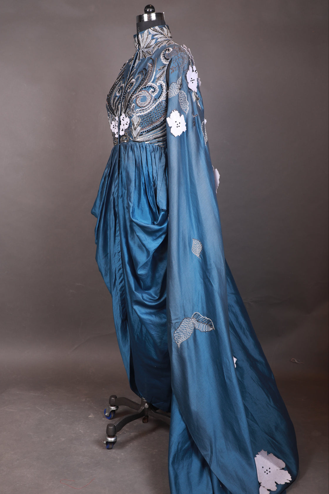 Blue dress with white floral embroidery on a gray background