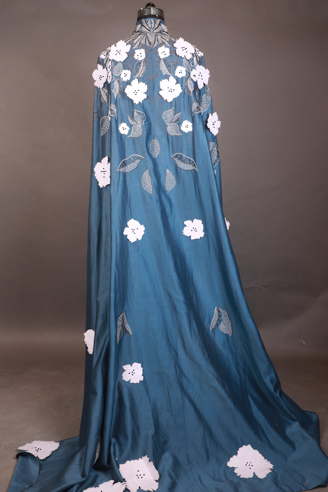 Blue dress with white floral embroidery on a gray background