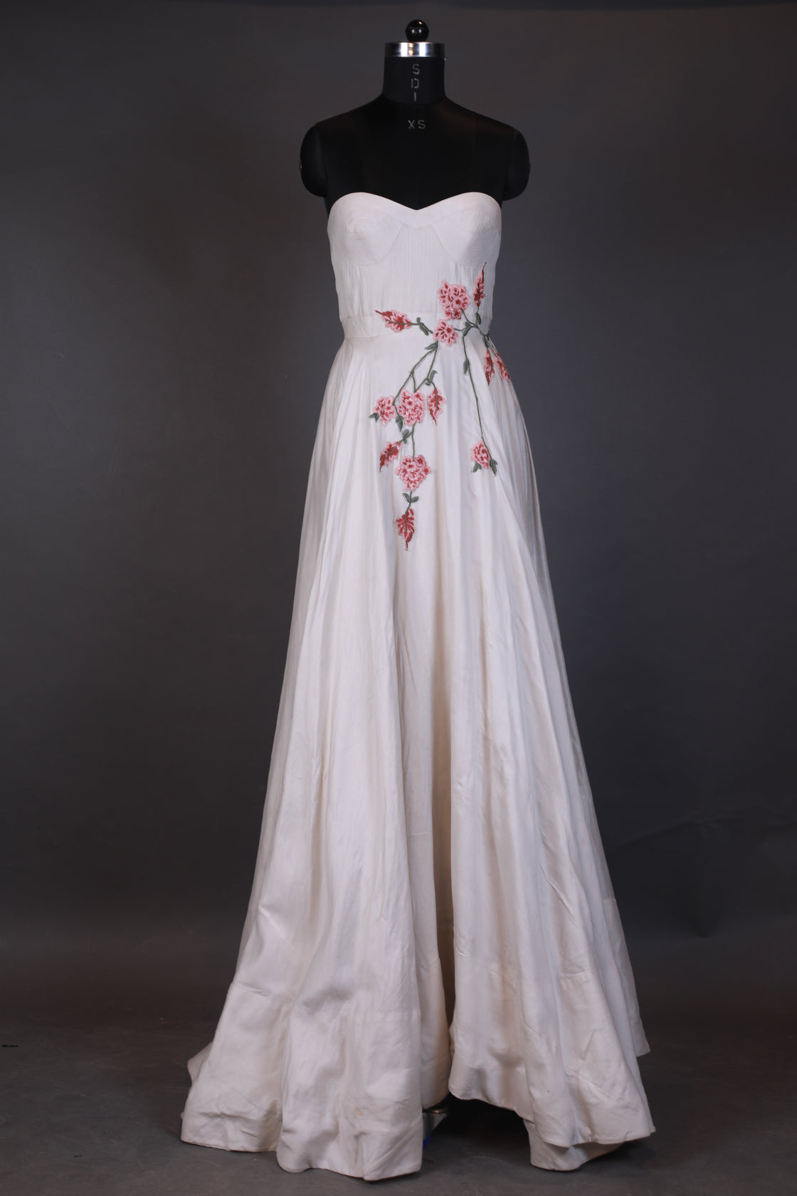 White dress with floral embroidery on a mannequin against a dark background