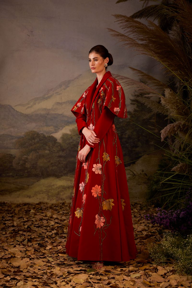 A red velvet fabric floor length gown with lapel neck line & extended cape