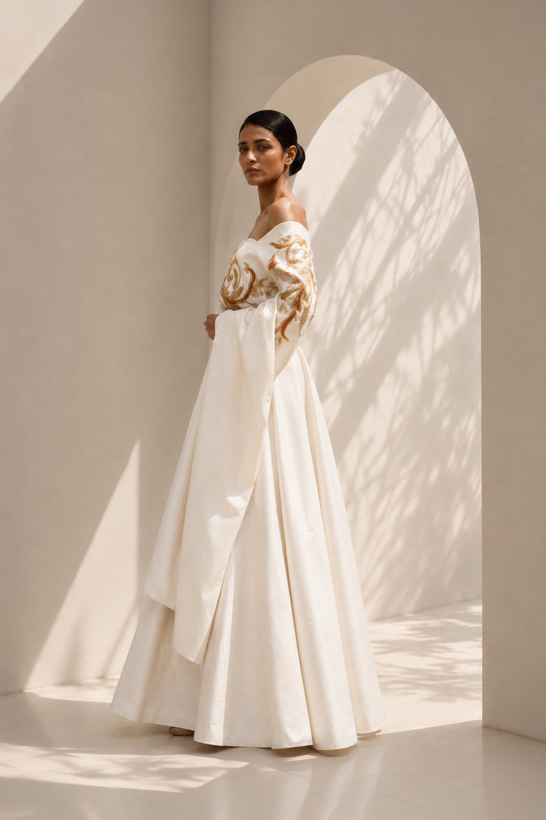 Ivory draped ensemble featuring off-shoulder embroidered stole, sculptural layering.