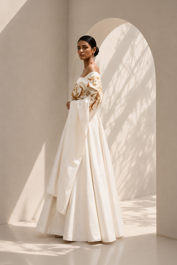 Ivory draped ensemble featuring off-shoulder embroidered stole, sculptural layering.