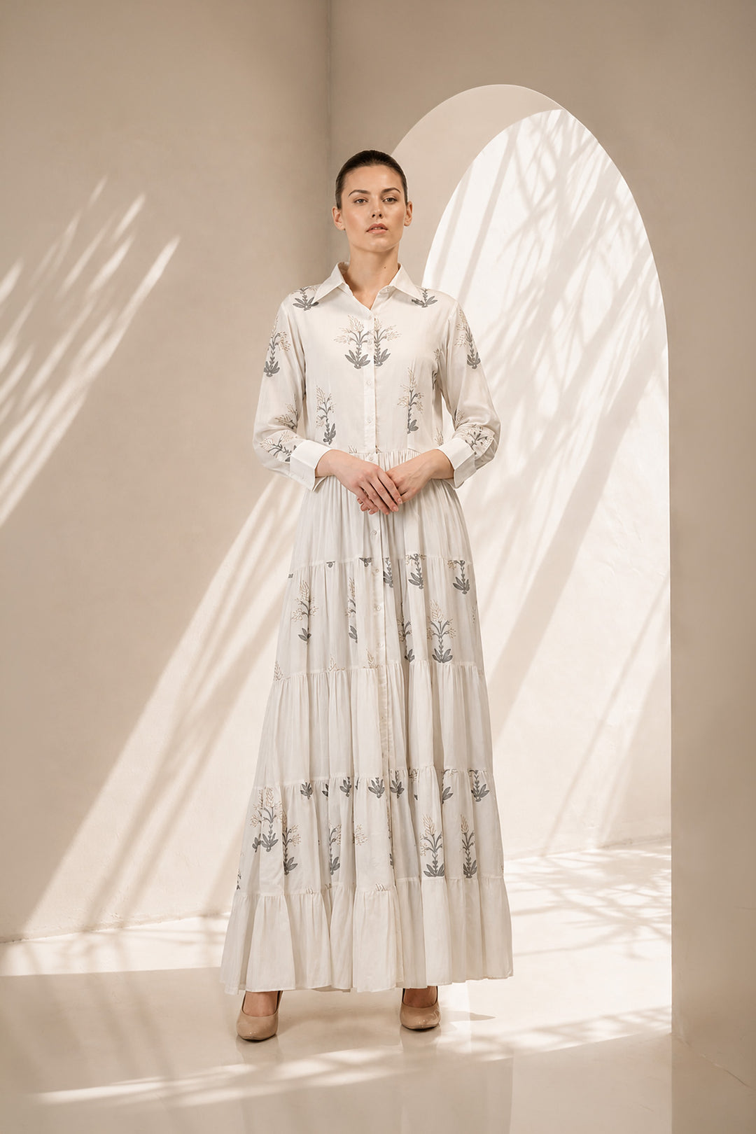 Ivory shirt dress adorned with delicate botanical prints, featuring a structured collar and cascading tiered silhouette.