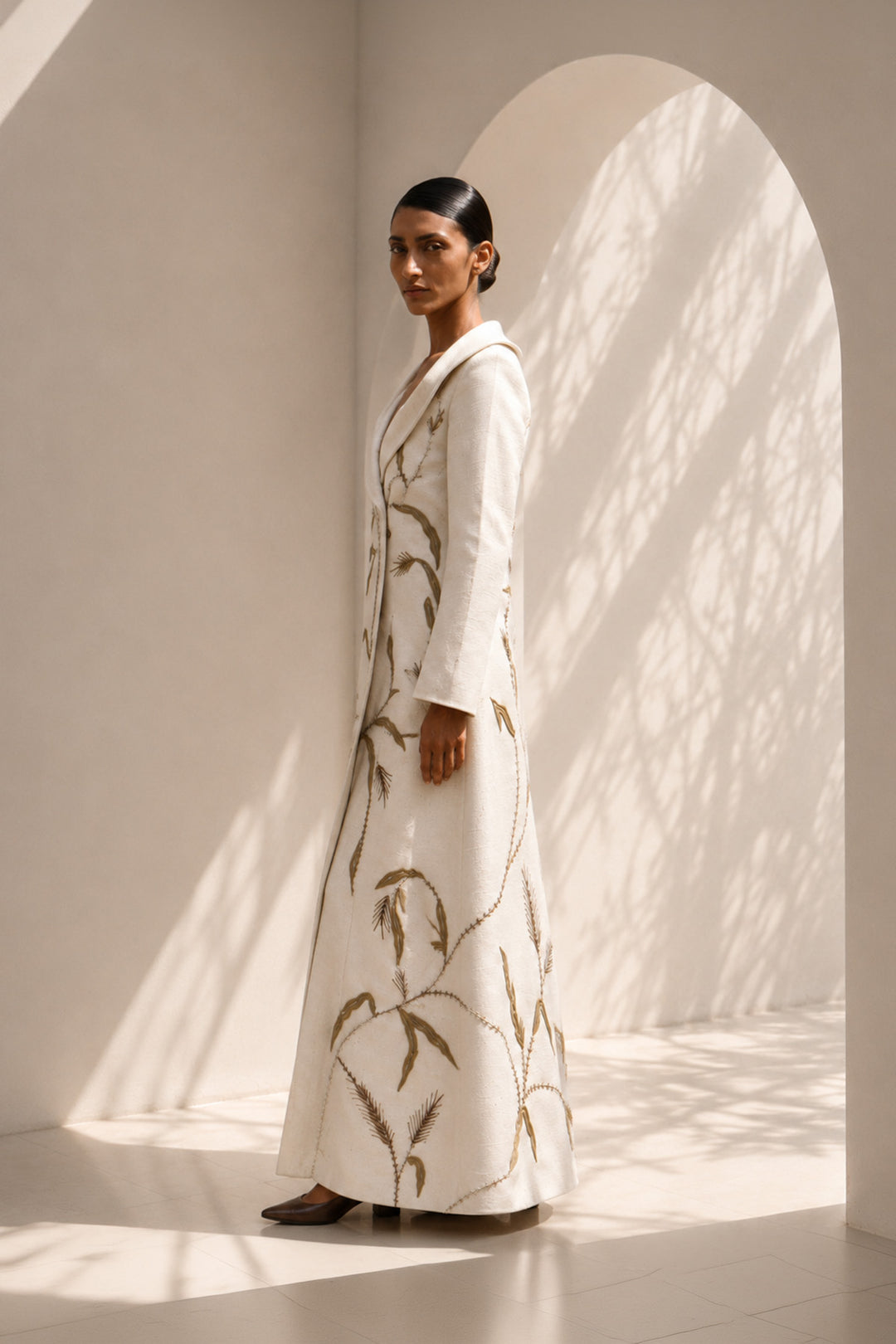 Ivory statement coat dress adorned with intricate embroidery, sculpted oversized shawl collar.