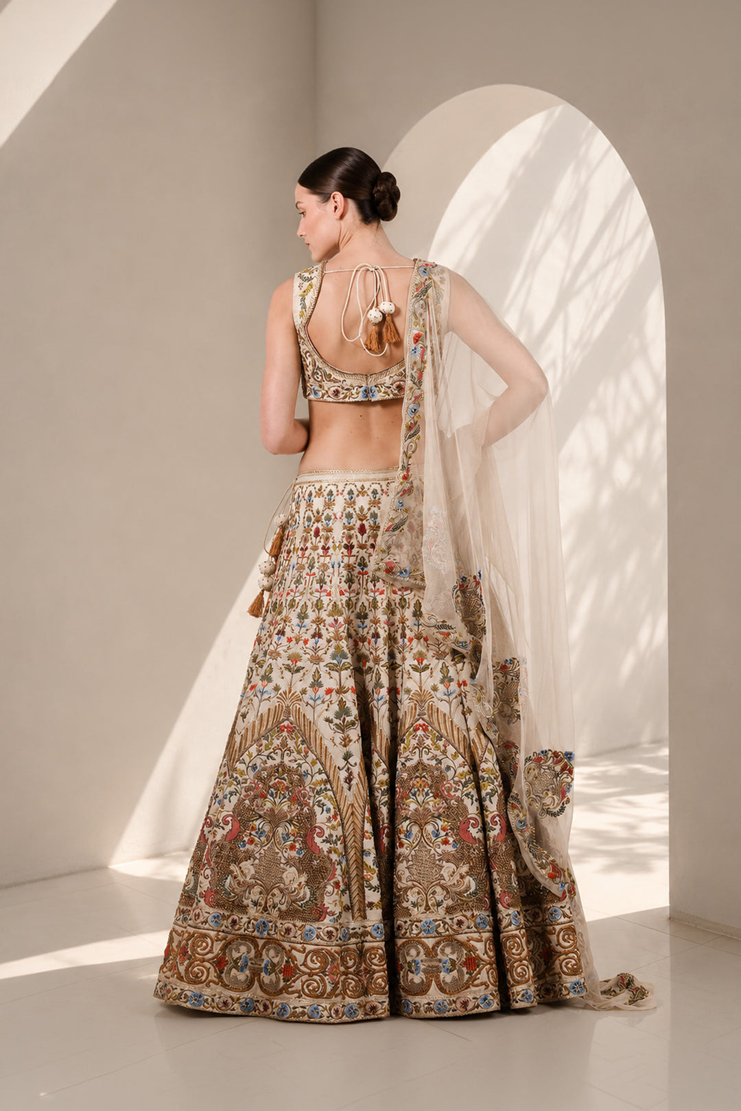Ivory lehenga set featuring sleeveless V-neck blouse with floral embroidery, a statement flared skirt with intricate embroidery on it and vibrant sheer dupatta.