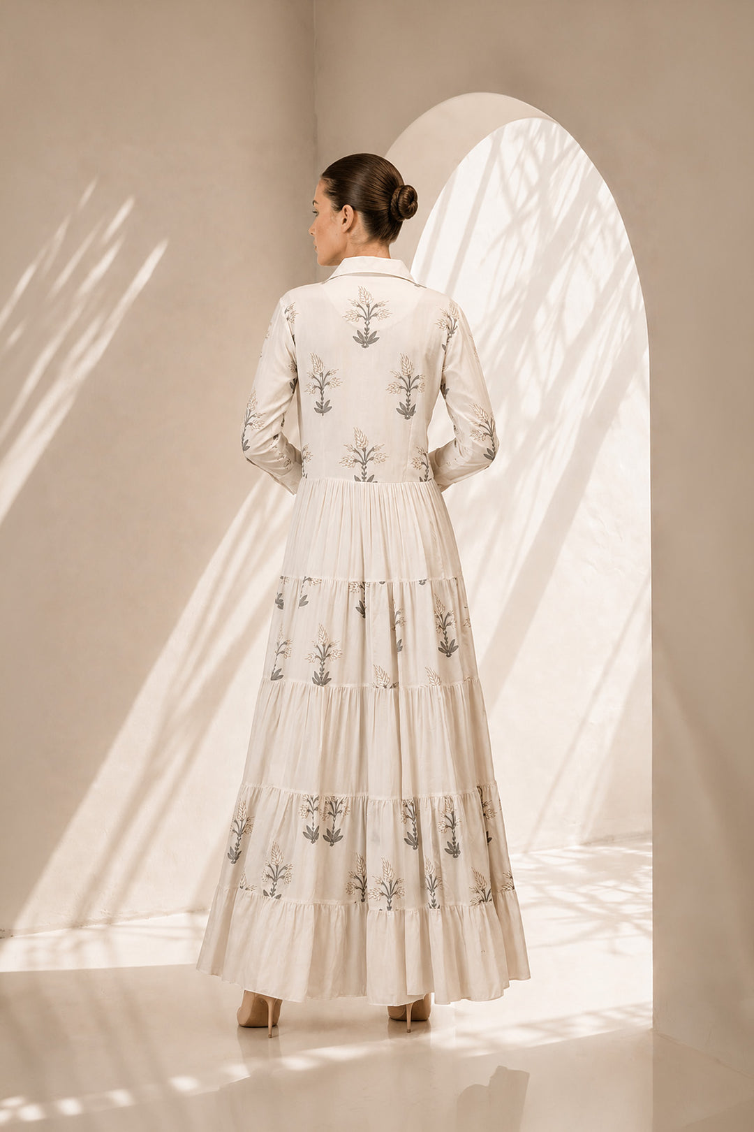 Ivory shirt dress adorned with delicate botanical prints, featuring a structured collar and cascading tiered silhouette.