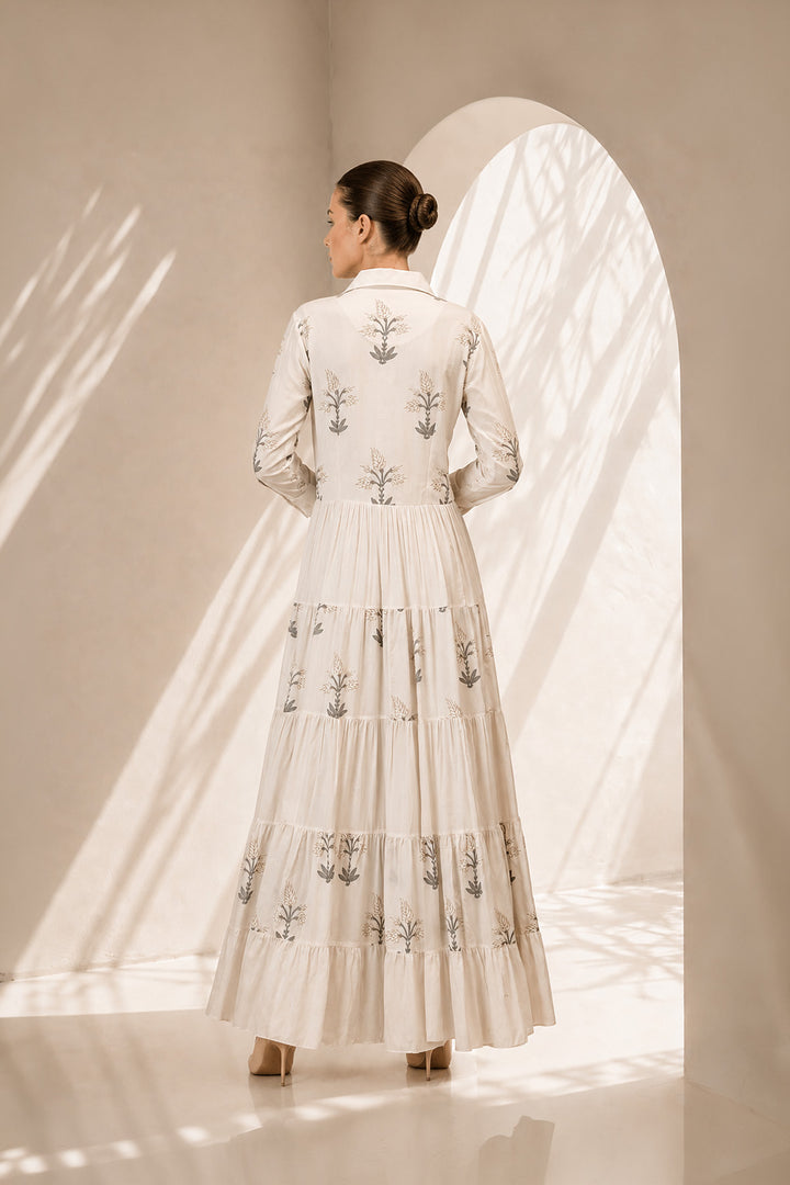 Ivory shirt dress adorned with delicate botanical prints, featuring a structured collar and cascading tiered silhouette.
