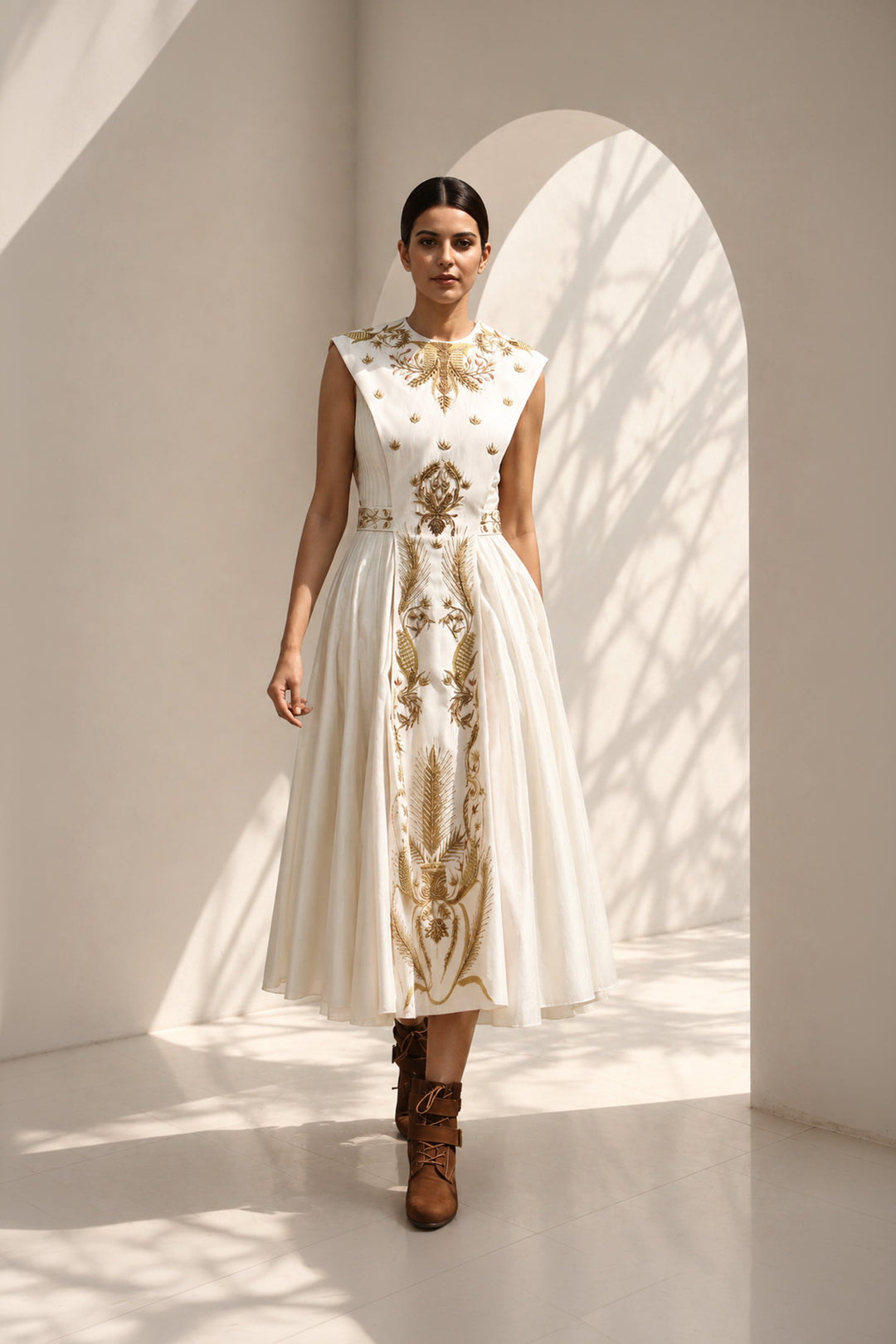 lvory midi dress adorned with embroidery, delicate pleated accents, blending structured elegance with fluid femininity.