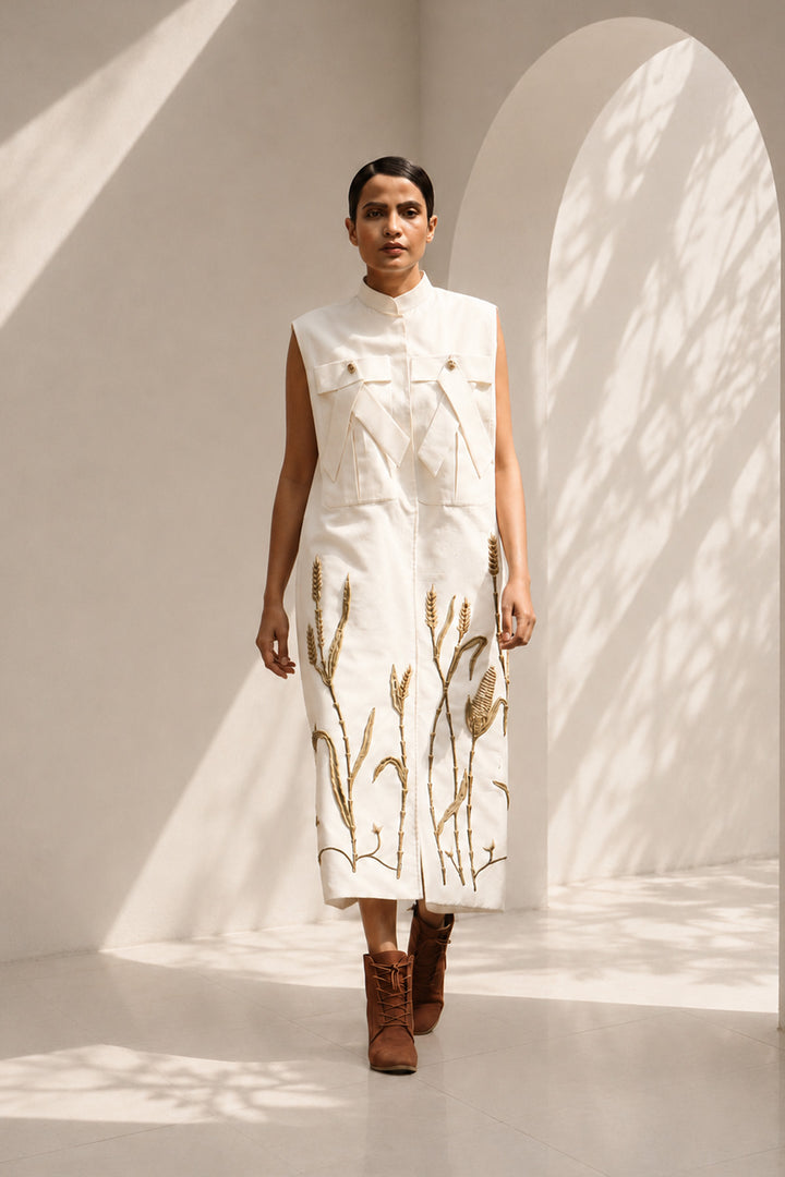 Ivory modern sleeveless statement dress featuring sculptural pocket detailing and intricate wheat-inspired embroidery.