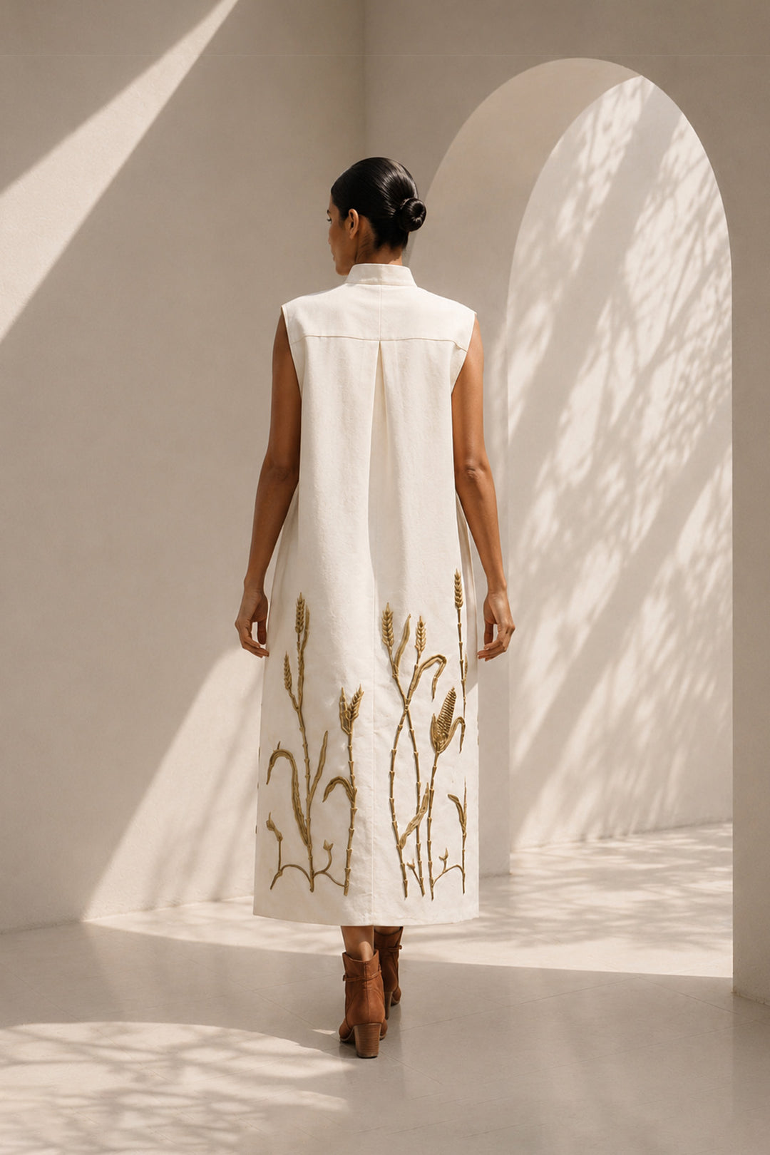 Ivory modern sleeveless statement dress featuring sculptural pocket detailing and intricate wheat-inspired embroidery.