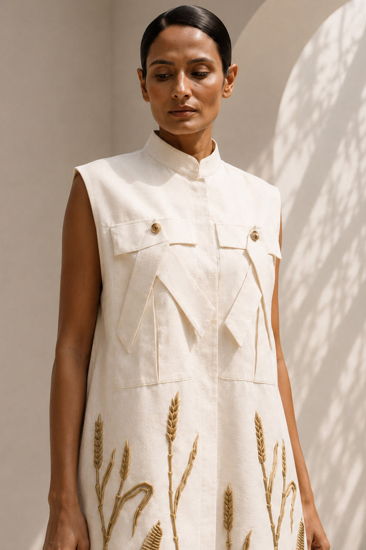 Ivory modern sleeveless statement dress featuring sculptural pocket detailing and intricate wheat-inspired embroidery.