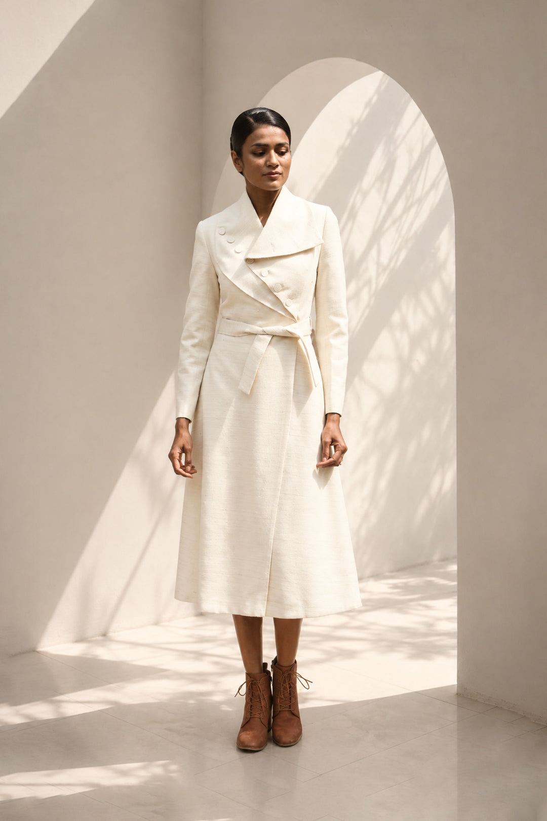 Ivory wrap coat dress featuring an architectural collar, asymmetrical button detailing, and a self-tie belt