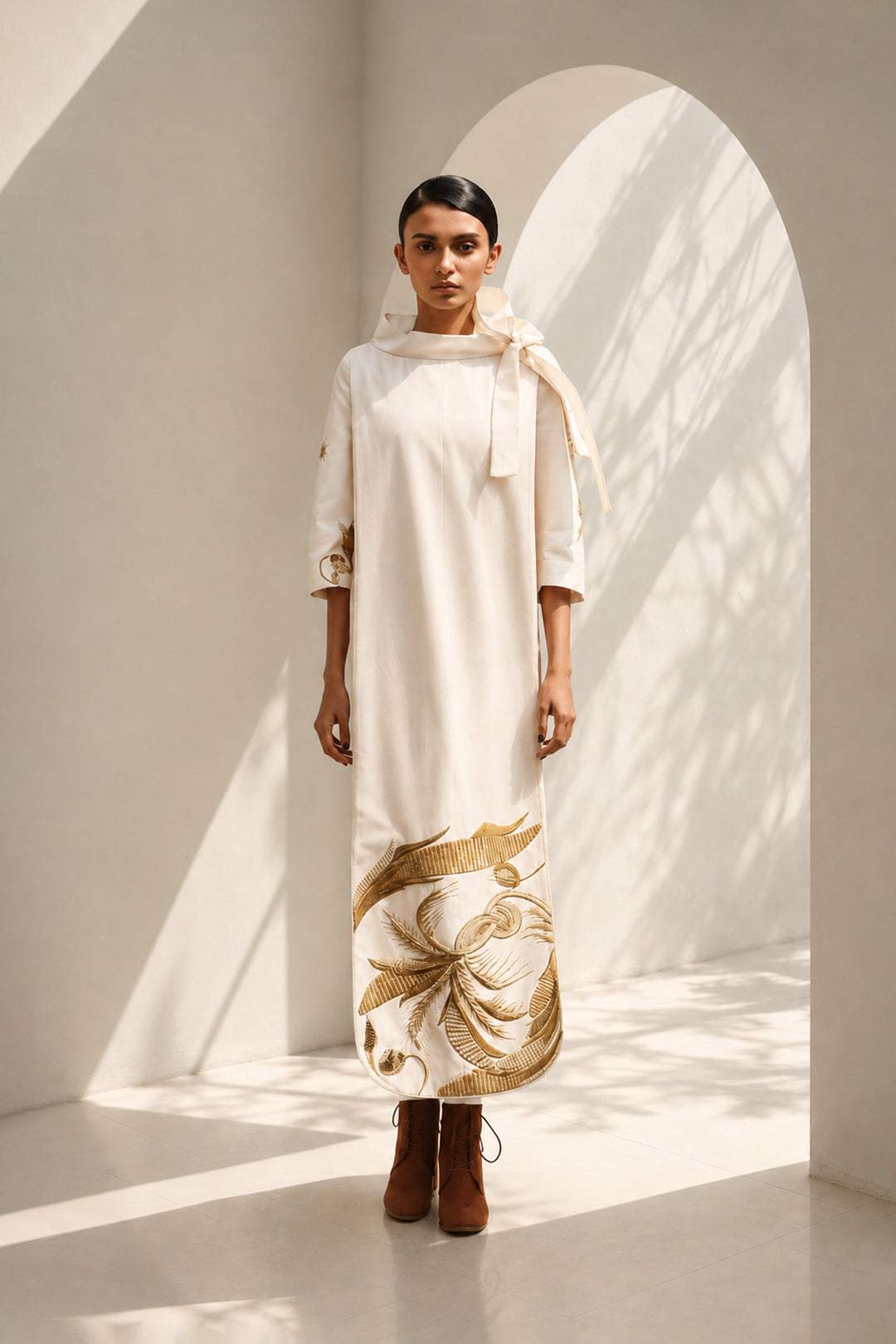 Ivory shift dress adorned with bold botanical artwork and a sculptural bow neckline.