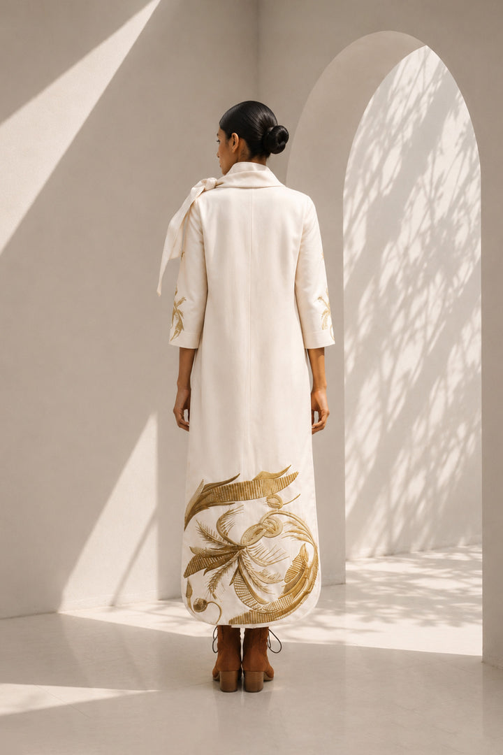 Ivory shift dress adorned with bold botanical artwork and a sculptural bow neckline.