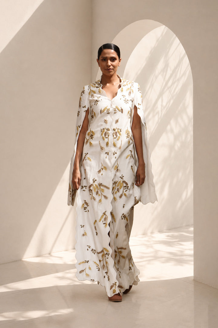 Ivory ensemble featuring flowing cape sleeves and all-over wheat-inspired embroidery.