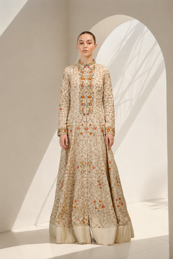 Woman wearing a long, embroidered dress in a minimalistic setting