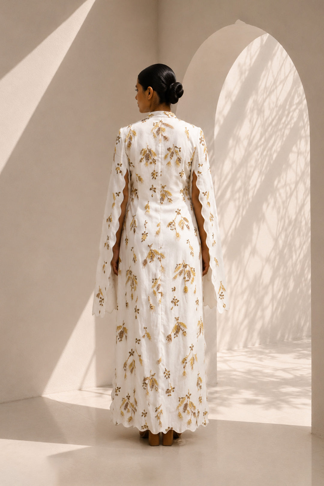 Ivory ensemble featuring flowing cape sleeves and all-over wheat-inspired embroidery.