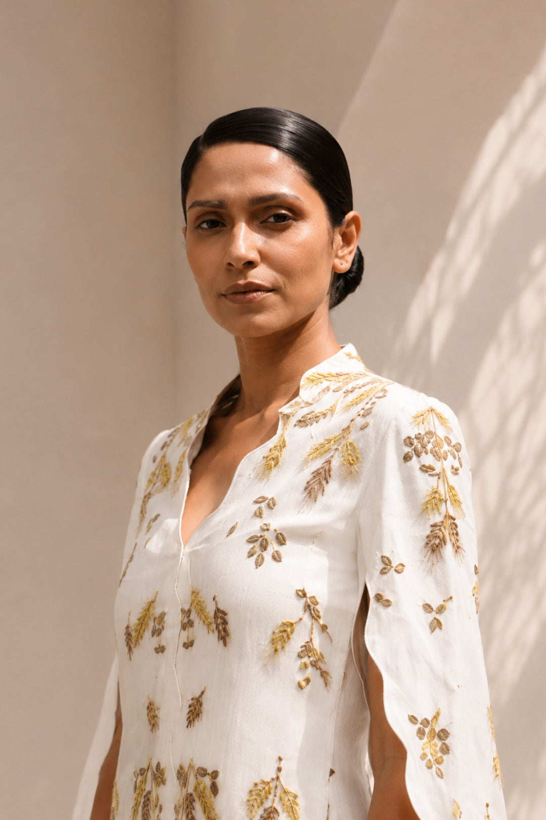 Ivory ensemble featuring flowing cape sleeves and all-over wheat-inspired embroidery.