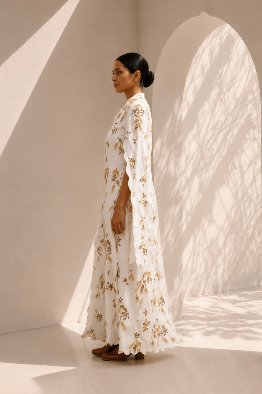 Ivory ensemble featuring flowing cape sleeves and all-over wheat-inspired embroidery.
