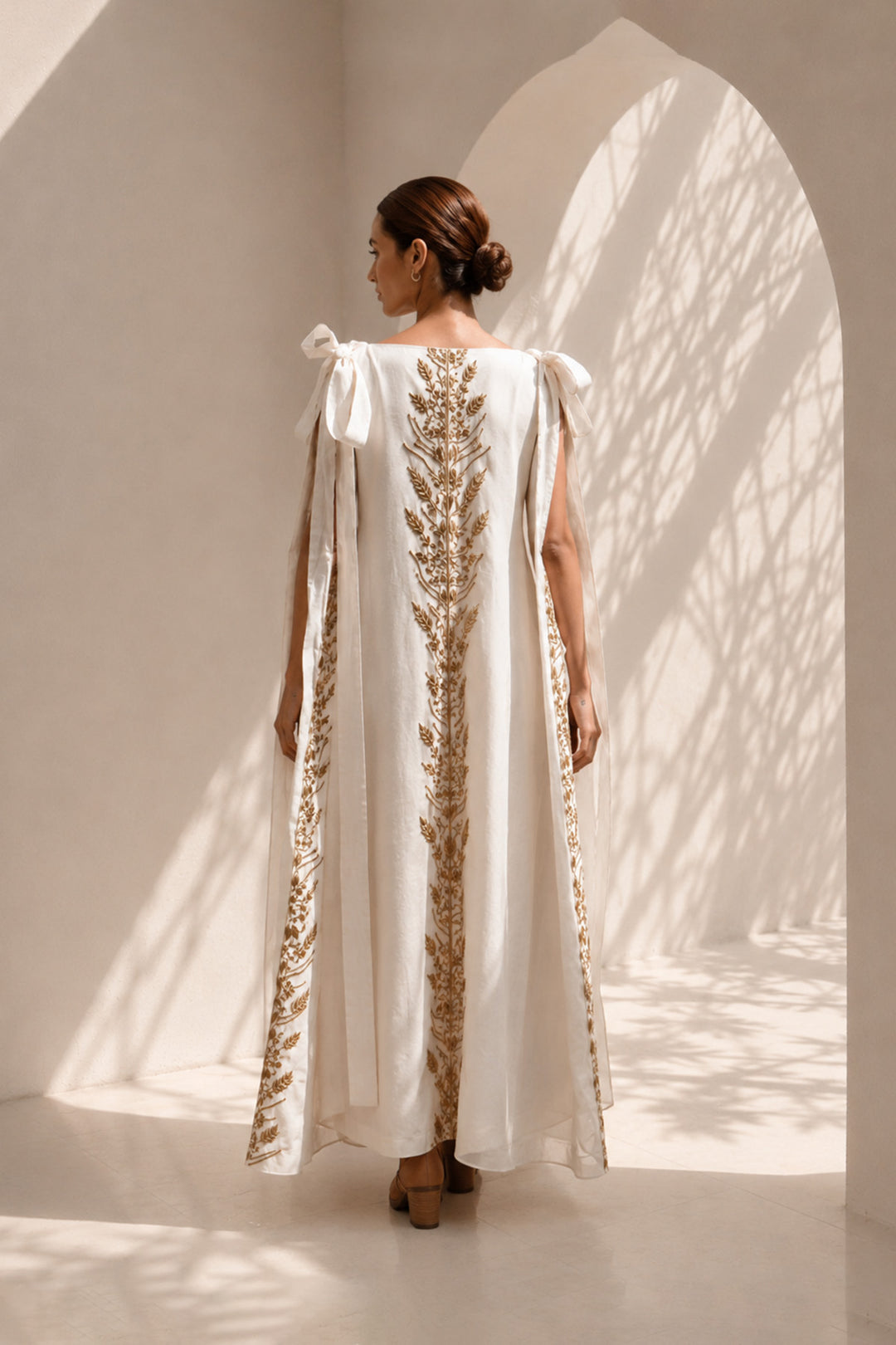 Ivory draped gown layered with a flowing embroidered cape