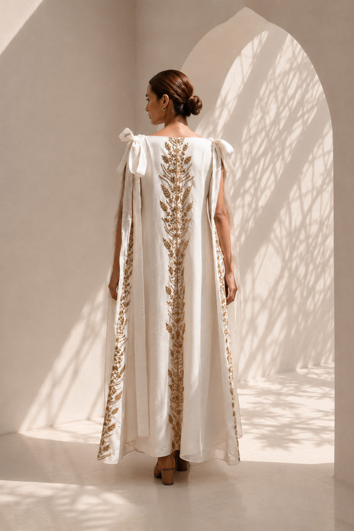 Ivory draped gown layered with a flowing embroidered cape