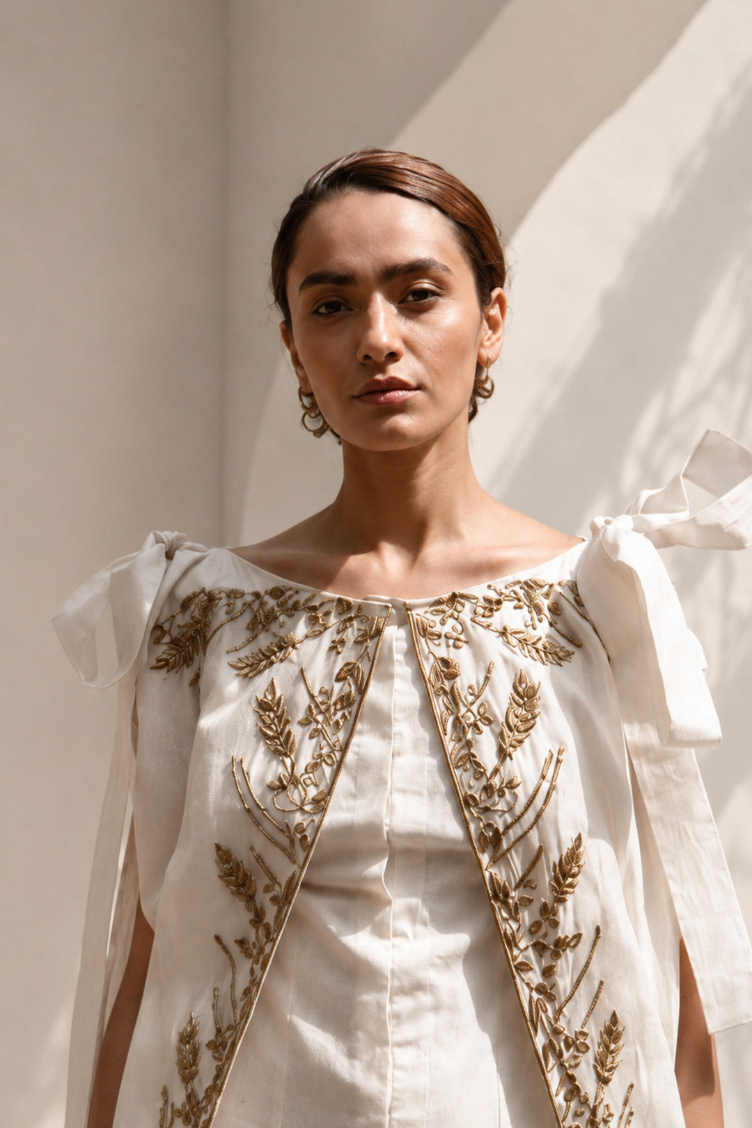 Ivory draped gown layered with a flowing embroidered cape