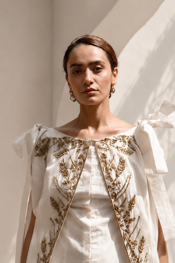 Ivory draped gown layered with a flowing embroidered cape