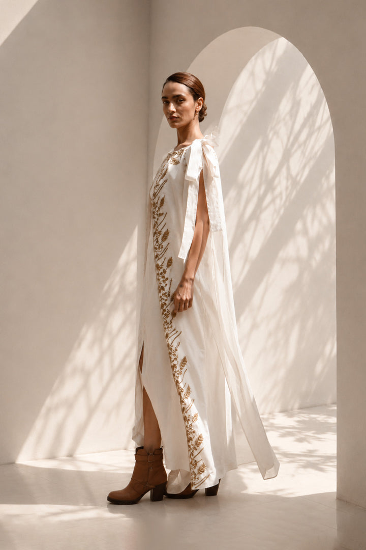 Ivory draped gown layered with a flowing embroidered cape