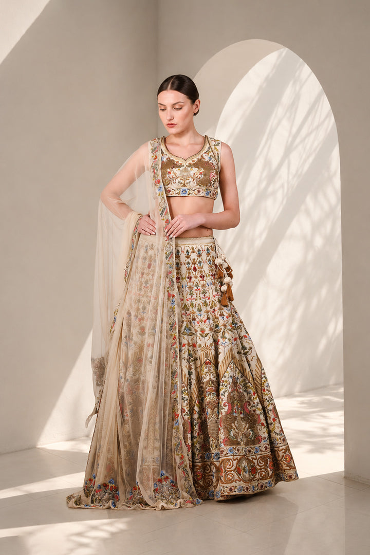Ivory lehenga set featuring sleeveless V-neck blouse with floral embroidery, a statement flared skirt with intricate embroidery on it and vibrant sheer dupatta.