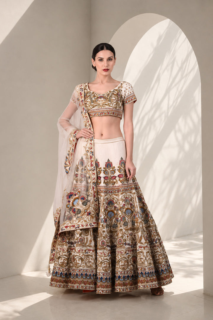 Ivory embroidered lehenga set featuring intricately embroidered blouse with scoop neckline and short sleeves, full flared lehenga paired with sheer dupatta.