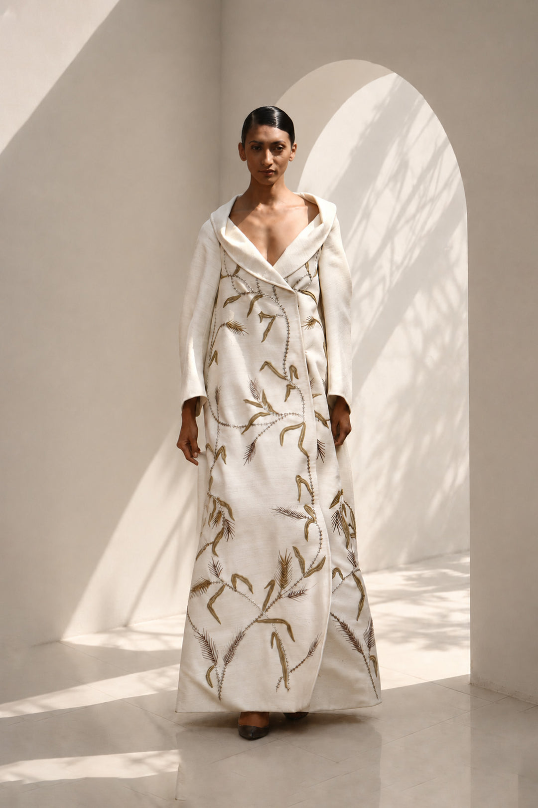 Ivory statement coat dress adorned with intricate embroidery, sculpted oversized shawl collar.