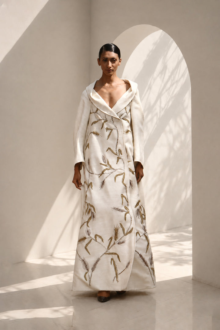 Ivory statement coat dress adorned with intricate embroidery, sculpted oversized shawl collar.