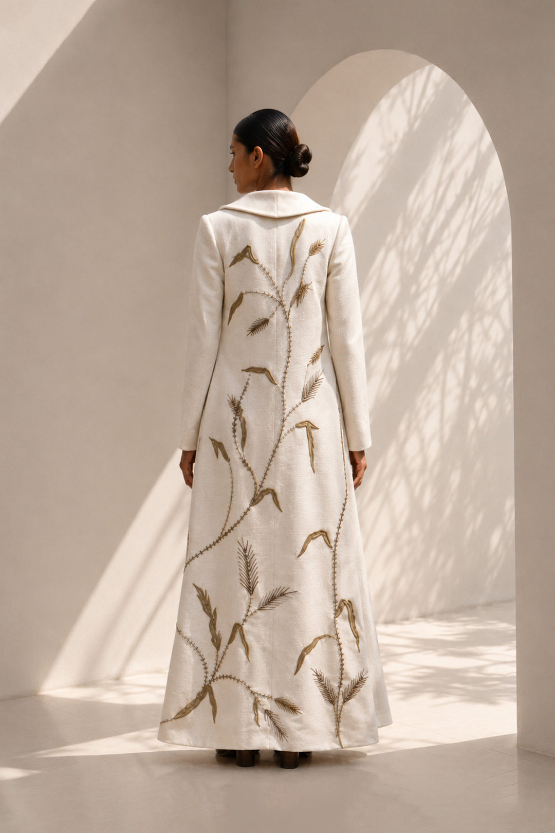 Ivory statement coat dress adorned with intricate embroidery, sculpted oversized shawl collar.