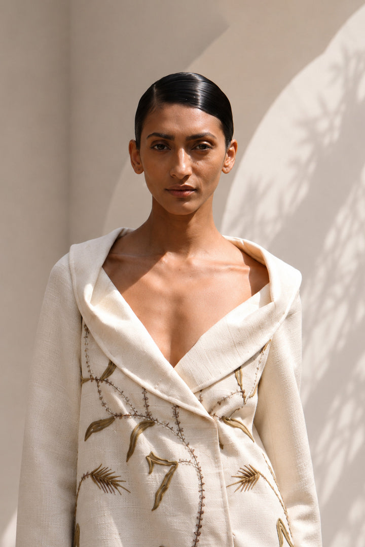 Ivory statement coat dress adorned with intricate embroidery, sculpted oversized shawl collar.