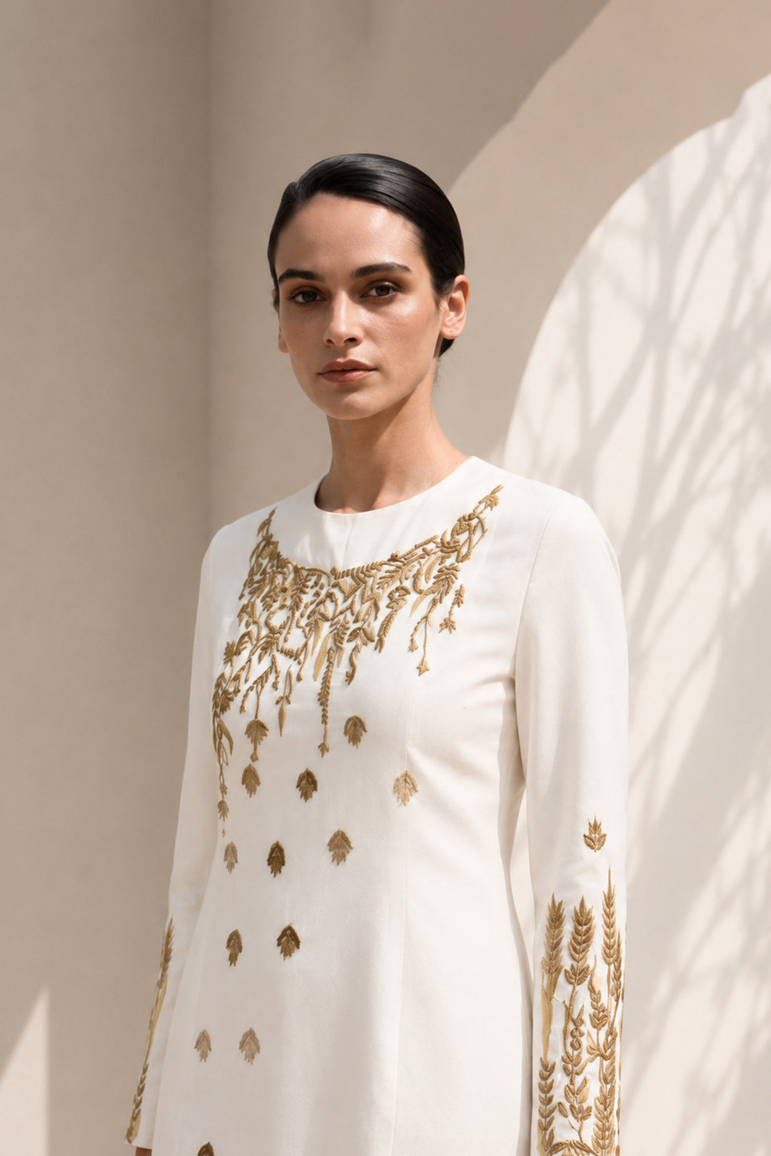 Ivory column dress adorned with delicate wheat-inspired embroidery, combining minimalist elegance.