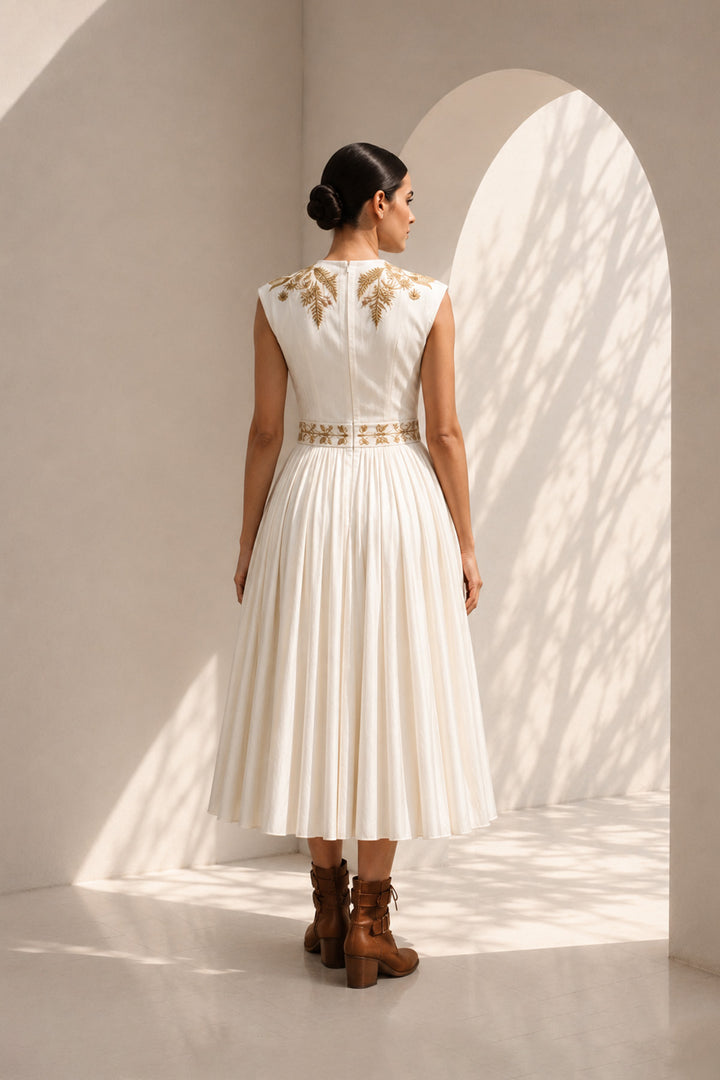 lvory midi dress adorned with embroidery, delicate pleated accents, blending structured elegance with fluid femininity.