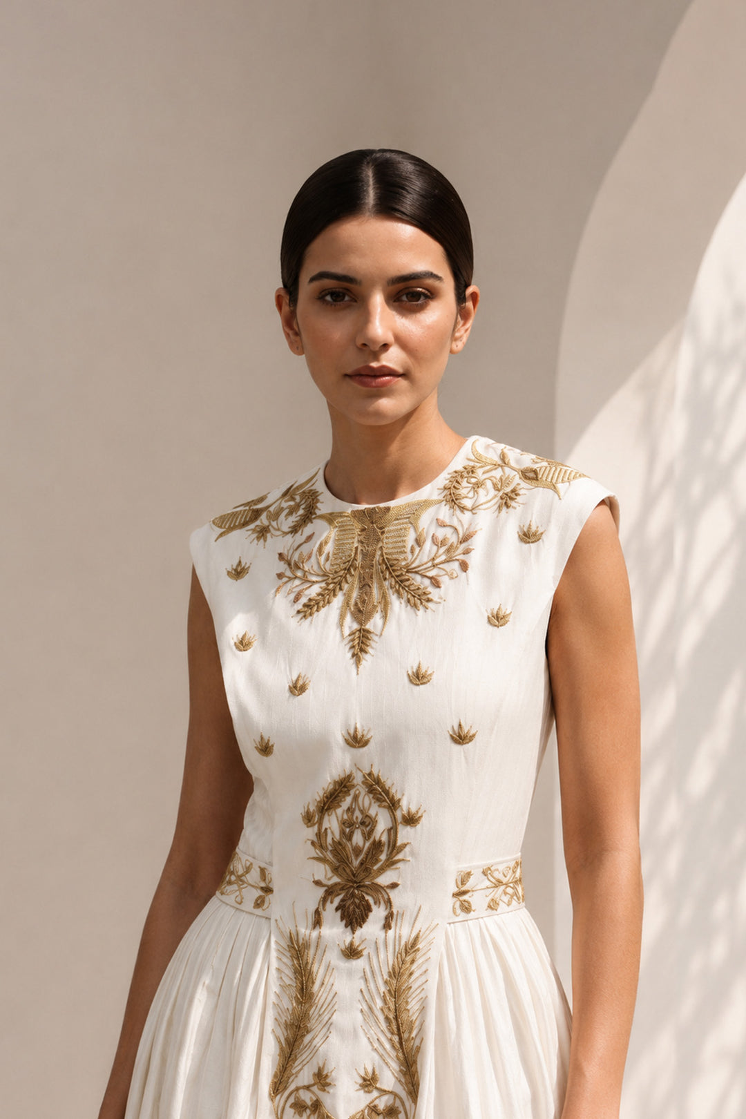lvory midi dress adorned with embroidery, delicate pleated accents, blending structured elegance with fluid femininity.
