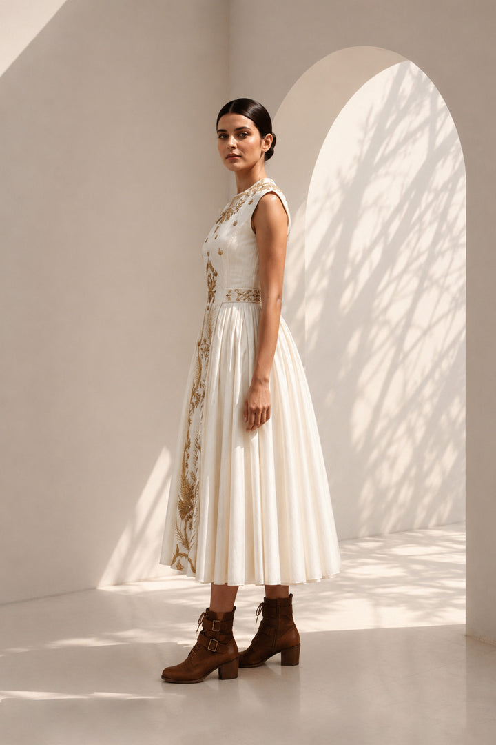 lvory midi dress adorned with embroidery, delicate pleated accents, blending structured elegance with fluid femininity.