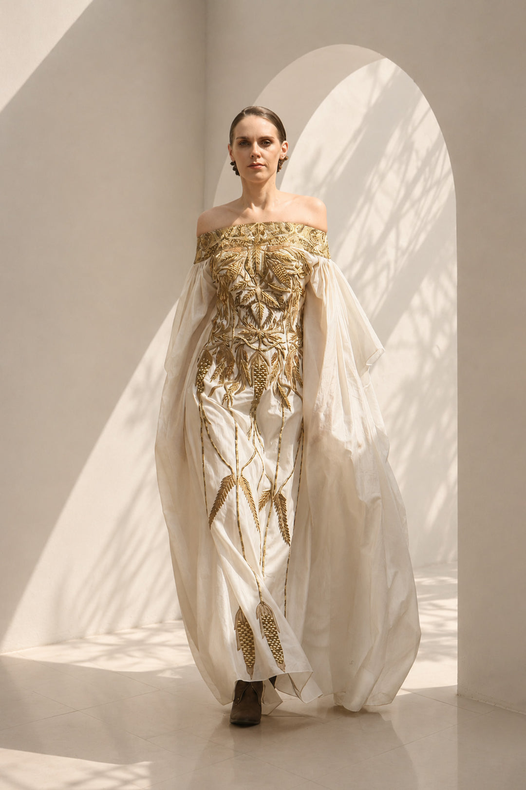Ivory statement gown featuring intricate embroidery, an off-shoulder neckline, and dramatic sheer sleeves.