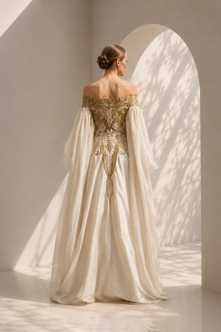 Ivory statement gown featuring intricate embroidery, an off-shoulder neckline, and dramatic sheer sleeves.