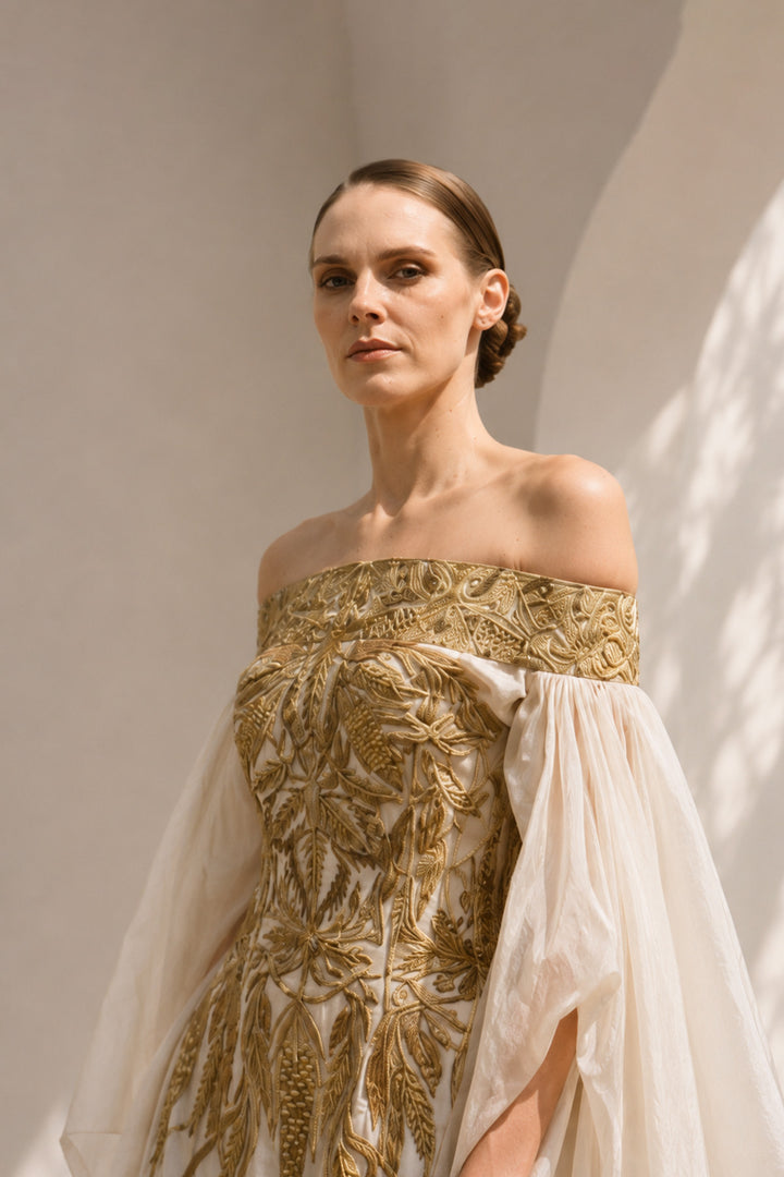 Ivory statement gown featuring intricate embroidery, an off-shoulder neckline, and dramatic sheer sleeves.
