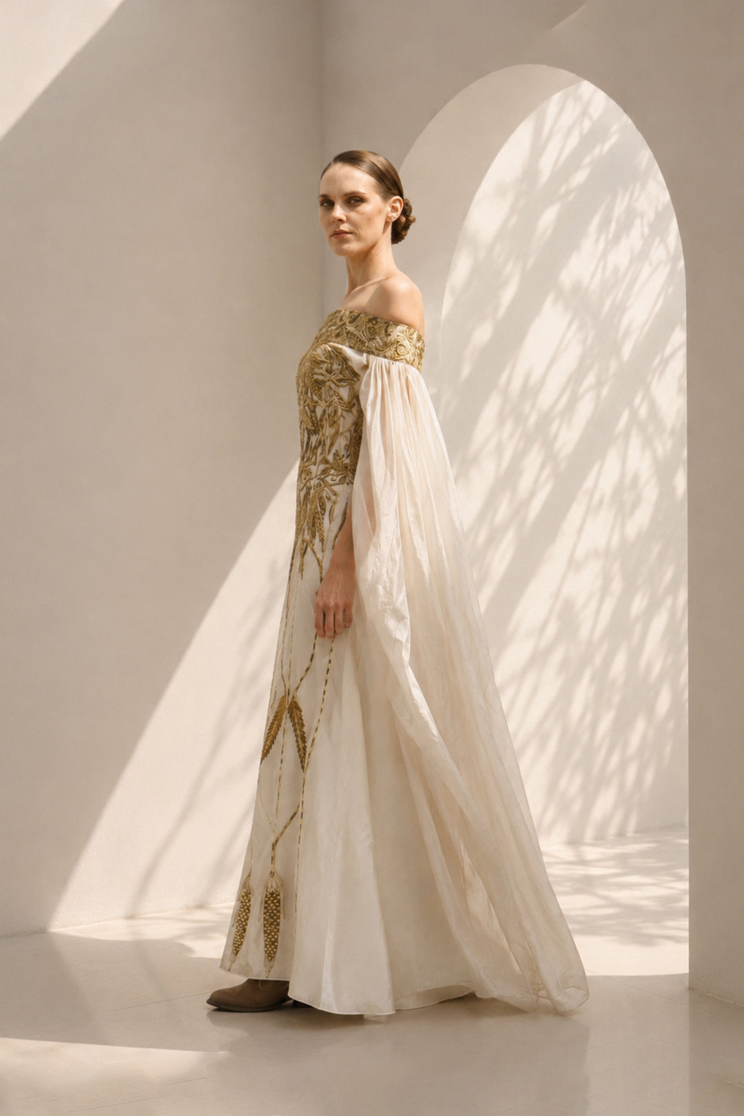 Ivory statement gown featuring intricate embroidery, an off-shoulder neckline, and dramatic sheer sleeves.