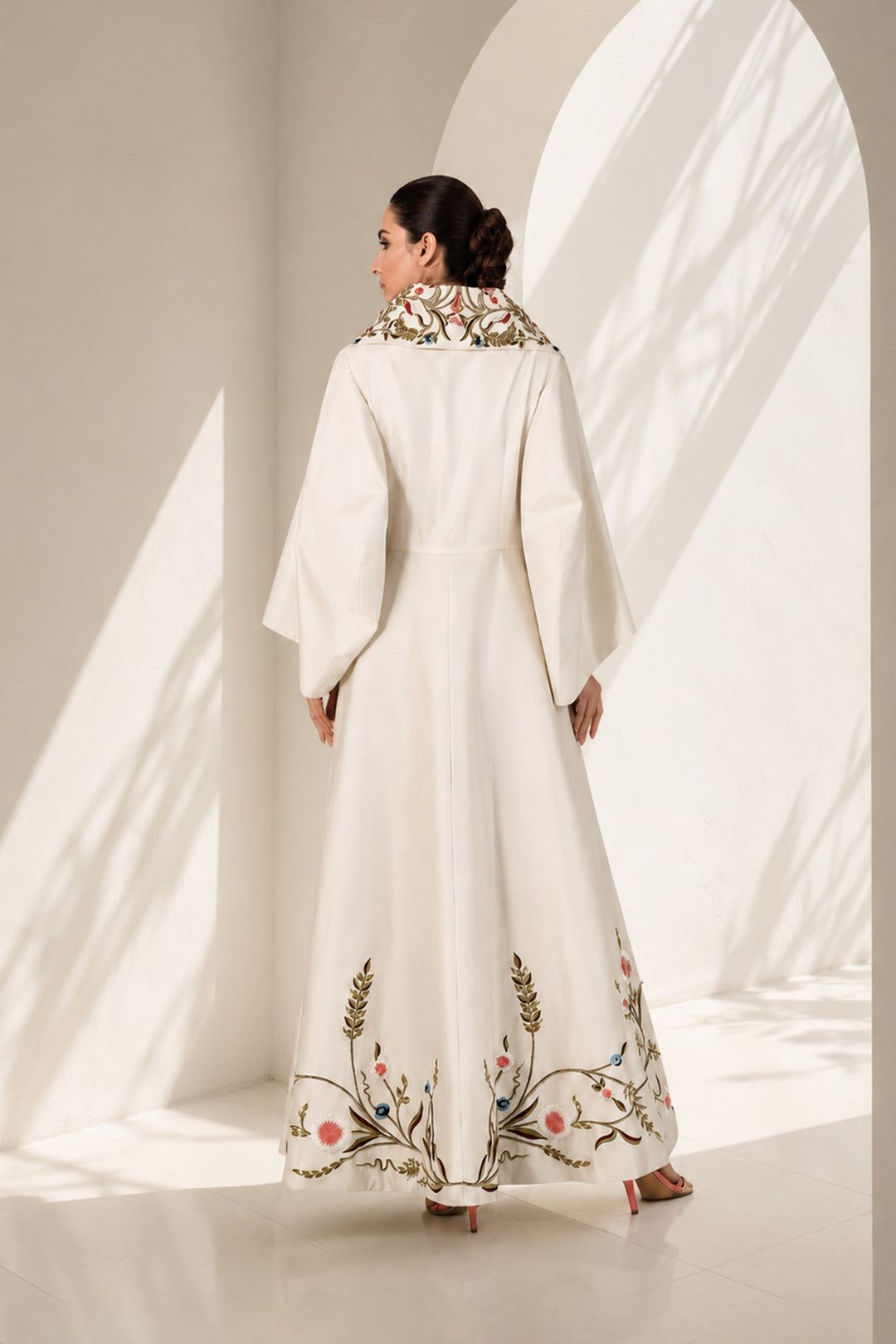 Ivory wrap gown adorned with embroidery, featuring shawl collar neckline,  bell sleeves and fluid drape.