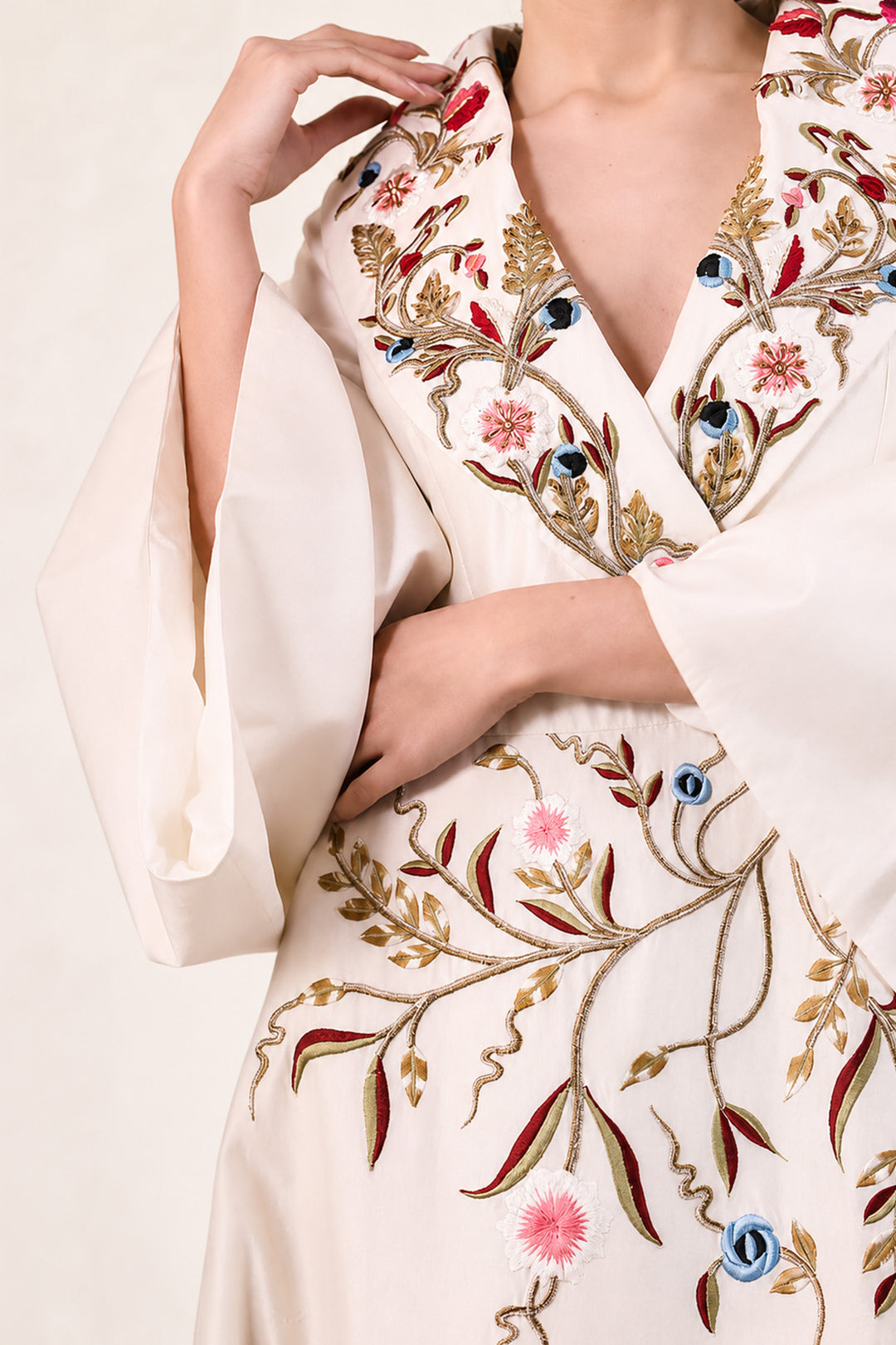 Ivory wrap gown adorned with embroidery, featuring shawl collar neckline,  bell sleeves and fluid drape.