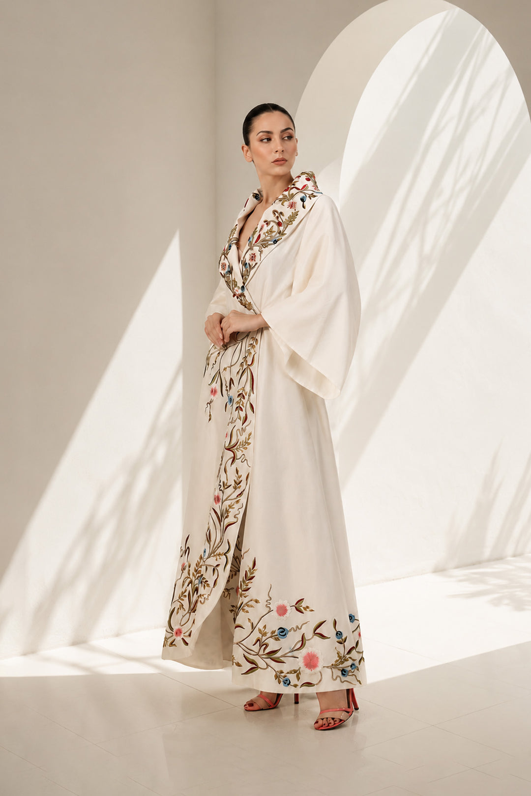 Ivory wrap gown adorned with embroidery, featuring shawl collar neckline,  bell sleeves and fluid drape.