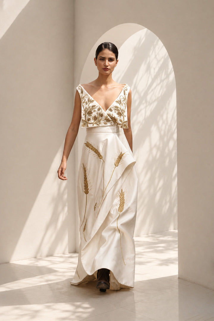 Ivory draped gown featuring intricately embroidered V-neck bodice and sculptural asymmetric drape.