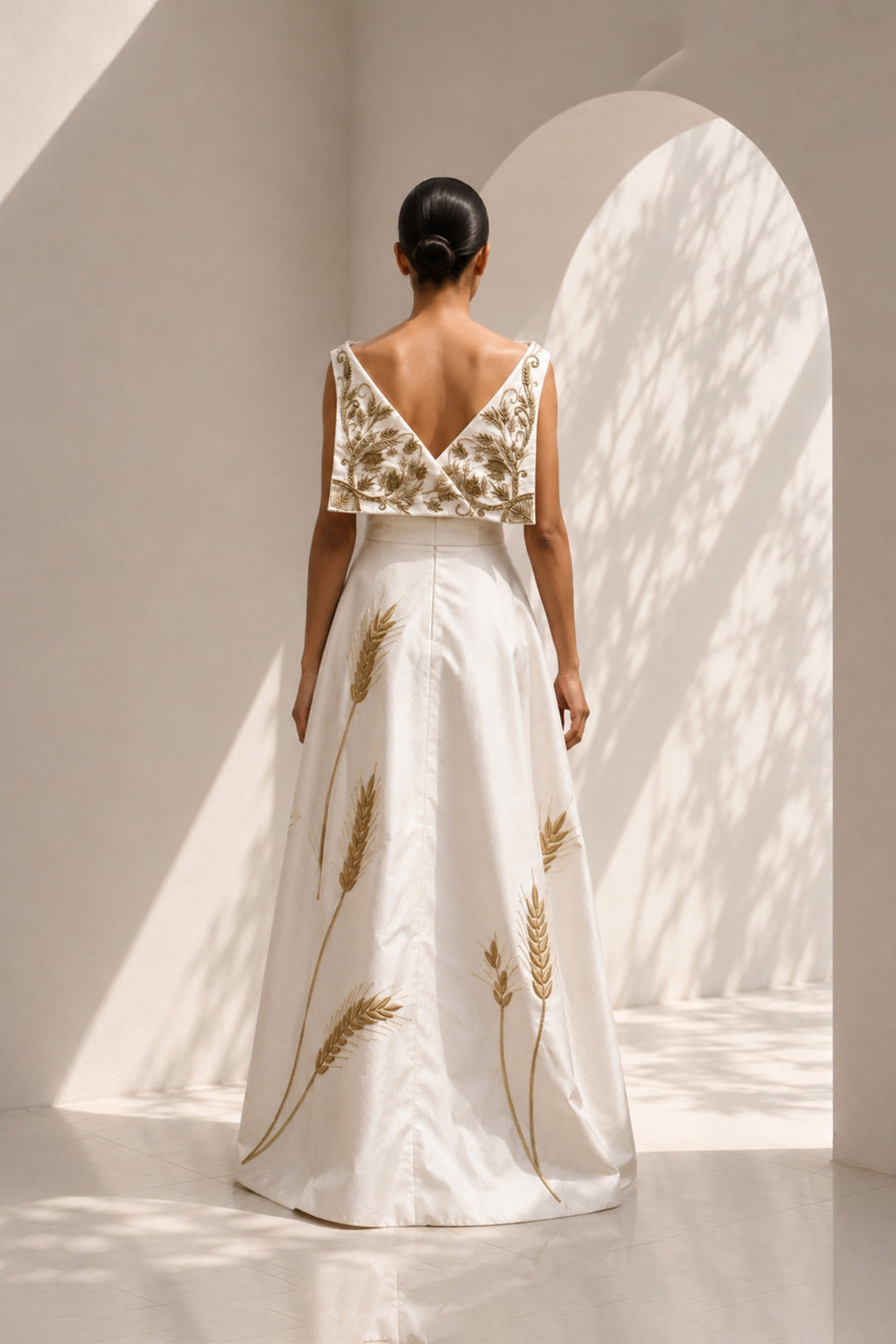 Ivory draped gown featuring intricately embroidered V-neck bodice and sculptural asymmetric drape.