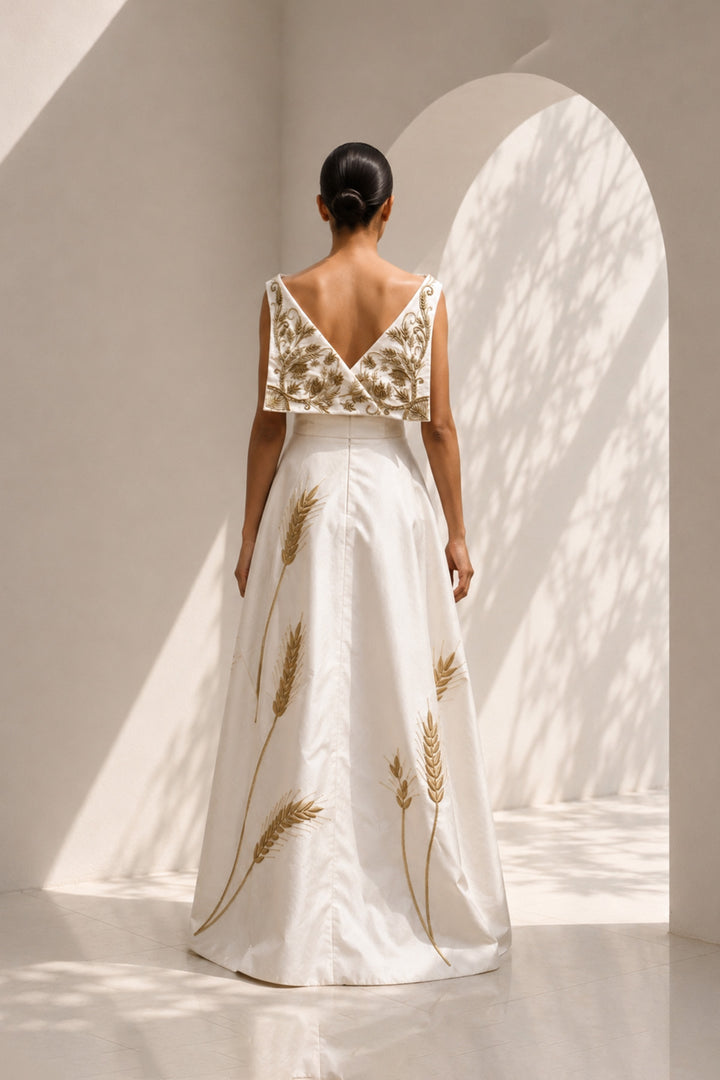 Ivory draped gown featuring intricately embroidered V-neck bodice and sculptural asymmetric drape.
