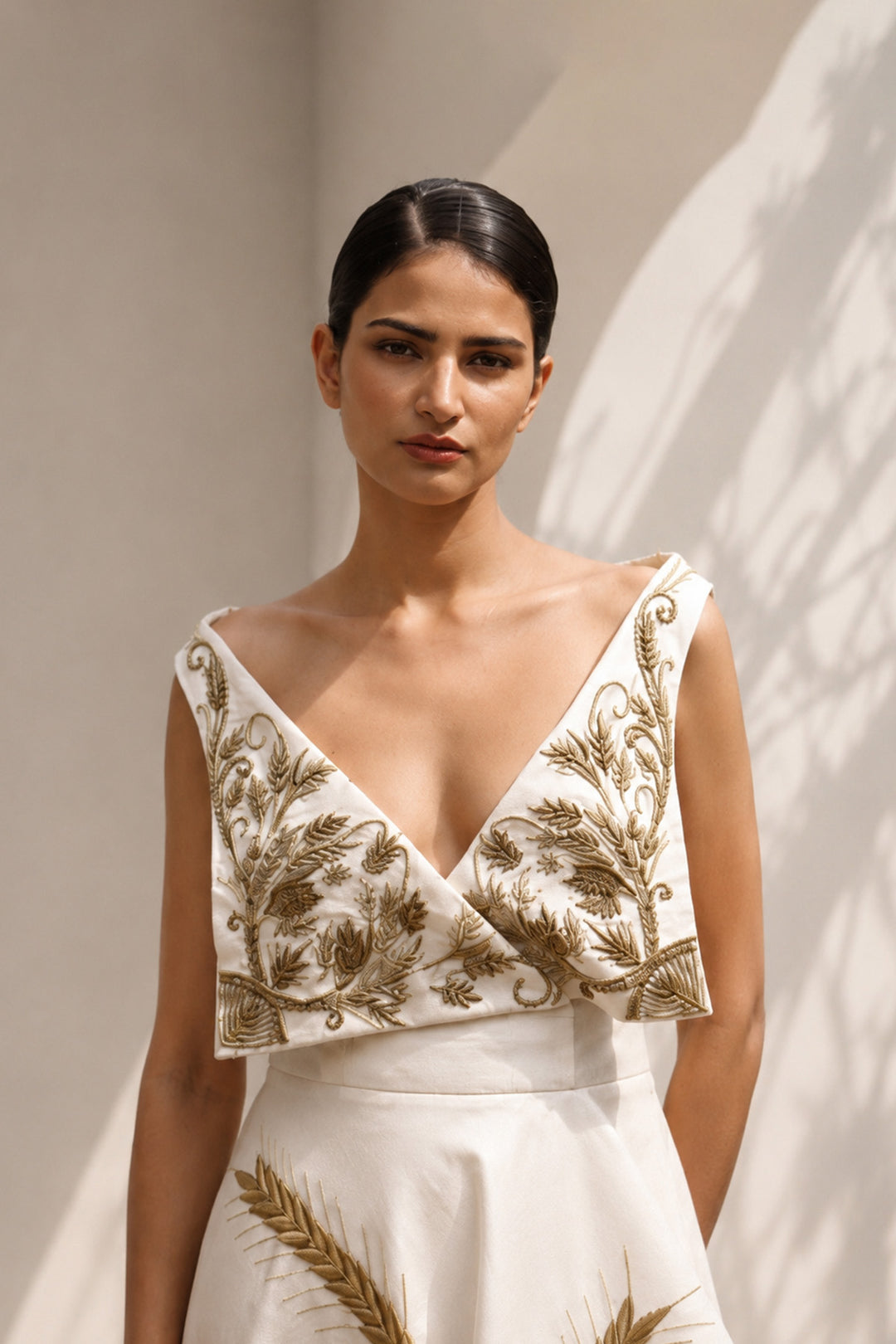 Ivory draped gown featuring intricately embroidered V-neck bodice and sculptural asymmetric drape.