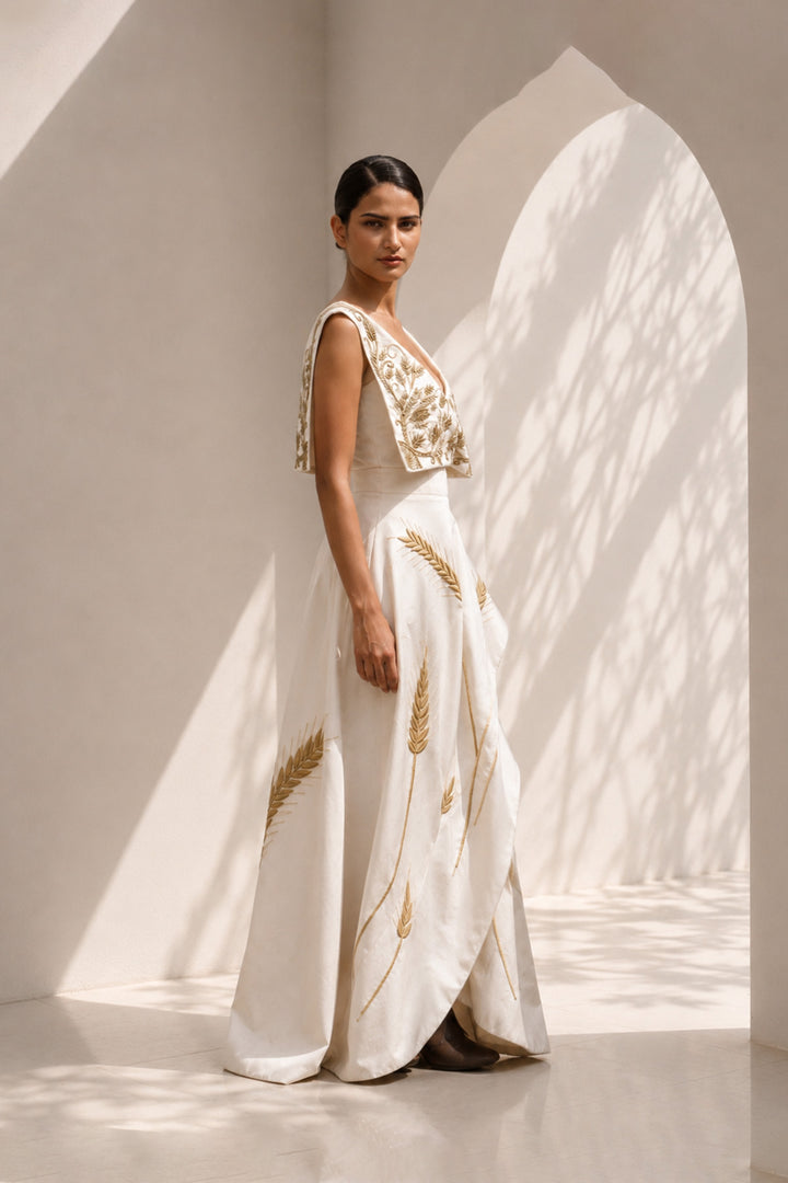 Ivory draped gown featuring intricately embroidered V-neck bodice and sculptural asymmetric drape.